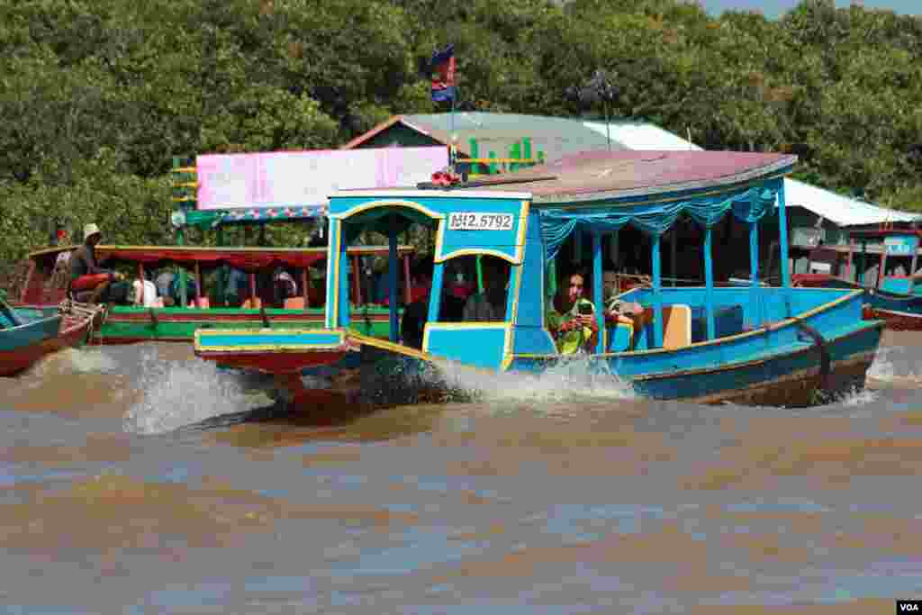 អ្នកទេសចរកំពុងថតរូប នៅលើបឹងទន្លេសាប ក្បែរភូមិកំពង់ភ្លុក ខេត្តសៀមរាប កាលពីថ្ងៃទី៥ ខែធ្នូ ឆ្នាំ២០១៥។ (នូវ ពៅលក្ខិណា/VOA) 