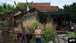ស្ត្រី​វៀតណាម​ម្នាក់​ឈរ​នៅ​ខាង​ក្រៅ​ផ្ទះ​របស់​នាង​នៅ​ក្នុង​ស្រុក Yen Thanh ខេត្ត Nghe An ប្រទេស​វៀតណាម កាលពី​ថ្ងៃទី២៧ ខែតុលា ឆ្នាំ២០១៩។