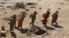 FILE - Women carry jerry cans of water from shallow wells dug in the sand along the Shabelle River bed, which is dry due to drought in Somalia's Shabelle region, March 19, 2016.