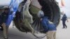 In this April 17, 2018 frame from video, a National Transportation Safety Board investigator examines damage to the engine of the Southwest Airlines plane that made an emergency landing at Philadelphia International Airport in Philadelphia.