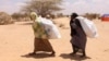FILE - Southern Somali women carry food aid donations from the UNHCR as they make their way to their refugee camp in Dollow, Somalia, Aug. 30, 2011. Hunger is again stalking the country, and the U.N. is appealing for aid.