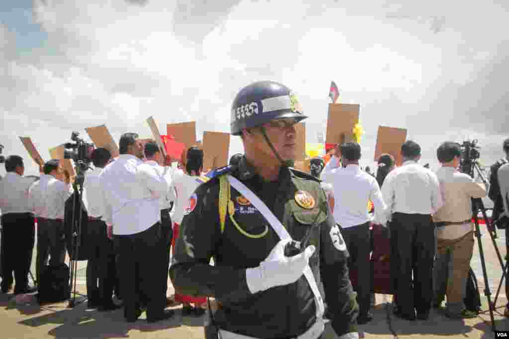 កងកម្លាំងសន្តិសុខធ្វើល្បាត ខណៈពេលប្រជាជនរង់ចាំទទួលស្វាគមន៍ការមកដល់របស់ប្រធានាធិបតីចិនលោក Xi Jinping នៅក្រុងភ្នំពេញ នាថ្ងៃទី១៣ ខែតុលា ឆ្នាំ២០១៦។ (ឡេង ឡែន/VOA) 