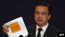Malaysia's Transport Minister Liow Tiong Lai holds up a preliminary disaster report on the fate of Malaysia Airlines flight MH17 which crashed in eastern Ukraine, released by the Dutch Safety Board (DSB), during a press conference in Putrajaya, outside Ku