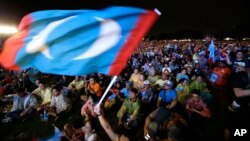 In this May 6, 2018 photo, supporters of former Malaysian strongman Mahathir Mohamad wave flag during an election campaign in Kuala Lumpur, Malaysia.