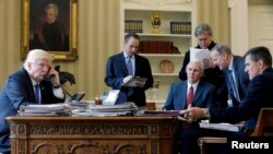 Le président américain Donald Trump avec, de gauche à droite, le chef d'état-major Reince Priebus, le vice-président Mike Pence, le conseiller principal Steve Bannon, le directeur de la communication Sean Spicer et le conseiller à la sécurité nationale Michael Flynn, au téléphone au Bureau ovale à la Maison Blanche, Washington, 28 janvier 2017. 