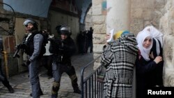 Des Palestiniennes se mettent à couvert alors que la police israélienne utilise des grenades assourdissantes pour disperser une foule qui tente d'entrer dans l'enceinte connue des musulmans comme Noble Sanctuaire et aux Juifs comme Mont du Temple dans la Vieille Ville de Jérusalem, 5 novembre 2014.