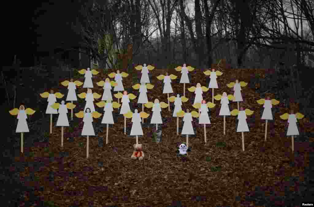 27 anges en bois placés dans un endroit boisé près d'une route menant vers l'école primaire Sandy Hook en mémoire des victimes du massacre
