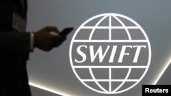 一路人在環球銀行金融電信協會標識撥打手機。