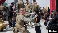 阿富汗首都喀佈爾哈米德卡爾扎伊國際機場。一名美國海軍陸戰隊成員正在給一名孩子喝水。