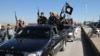 In this photo released on May 4, 2015, by a militant website, which has been verified and is consistent with other AP reporting, Islamic State militants pass by a convoy in Tel Abyad town, northeast Syria.