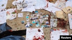 Des papiers d'identité nationaux tachés de sang et des photos d'électeurs devant un centre d'inscription des électeurs après un attentat-suicide à Kaboul, le 22 avril 2018.