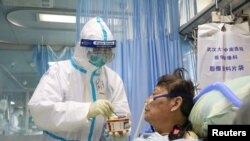 武漢大學中南醫院隔離病房中的一名護士星期六（2月8日）正在照顧一名病毒感染者。
