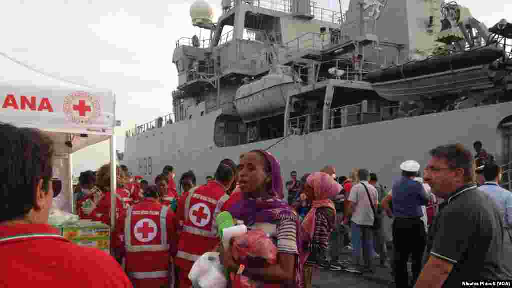 Le personnel de la Croix Rouge italienne accueille les migrants qui arrivent dans le port de Catane, Sicile, 6 octobre 2015 (Nicolas Pinault/VOA).