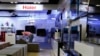 FILE - An employee arranges stools at a section displaying Haier television sets inside a Suning store in Shanghai.