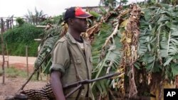 Un rebelle non identifié porte une mitrailleuse à environ 20 kilomètres de Masisi, RDC, 4 novembre 2005. 