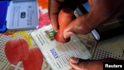 Un agent électoral appose le sceau sur le bulletin d’un électeur qui vient de voter lors des législatives à Abidjan, Côte d’Ivoire, 18 décembre 2016.