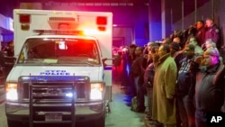 Dolientes saludan el paso de una ambulancia con los cadáveres de los dos policías asesinados cuando eran transportados desde el Centro Médico Woodhull, en Nueva York. 