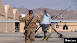 Un aviateur américain guide un drone Reaper MQ-9 de la Force aérienne américaine sur la piste de l'aérodrome de Kandahar en Afghanistan, le 9 mars 2016.
