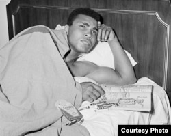 រូបលោក Muhammad Ali និង​សៀវភៅ​គូរពណ៌មួយក្បាលស្តីពី​មន្ត្រី​យោធា ក្នុង​អំឡុងពេល​ដែល​លោក Ali កំពុង​គិត​ពិចារណាអំពី​ការ​ឆ្លើយតប​របស់​លោក​ទៅ​នឹង​សេចក្តី​ប្រកាស​បិទ​សិទ្ធិ​ប្រដាល់​របស់​លោក​ កាលពី​ឆ្នាំ១៩៦៧។ (រូបថតផ្តល់​ឲ្យ​ដោយ George Kalinsky)