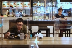 台北餐館在新冠疫情期間採取措施，吃午餐的顧客之間隔著塑料屏並保持距離。 （2021年5月12日）