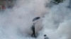 A protester walks in tear gas fired by riot policemen in Hong Kong's financial Central district outside the government headquarters on September 28, 2014.