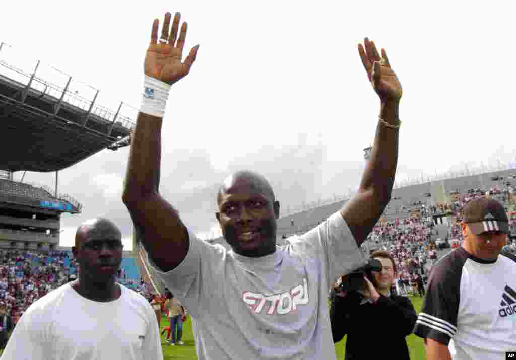 L'ancien footballeur libérien George Weah , à droite, salue la foule au cours du match de son jubilé joué à Marseille, au Sud de la France, samedi 11 juin 2005. Weah a annoncé sa candidat aux prochaines élections pour le Sénat après au Liberia.