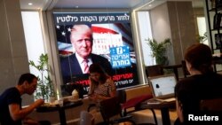 Quelques personnes regardent la soirée électorale du nouveau président américain Donald Trump sur un écran dans une cafétéria à Tel Aviv, en Israël, le 9 novembre 2016. 
