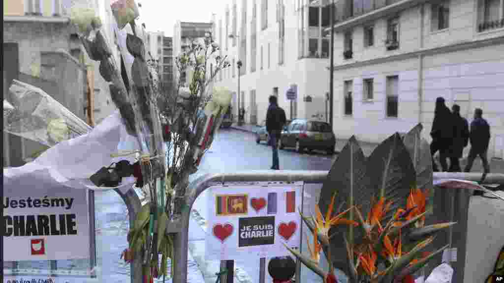 Des fleurs sont attachées à la clôture de sécurité devant le siège de Charlie Hebdo une semaine après l'attaque sur le journal, Paris, France, le 14 janvier 2015.