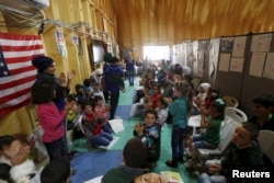 FILE - Syrian refugee children play as they wait with their families to register at the U.S. processing center for Syrian refugees, during a media tour held by the U.S. Embassy in Jordan, in Amman, Jordan, April 6, 2016.