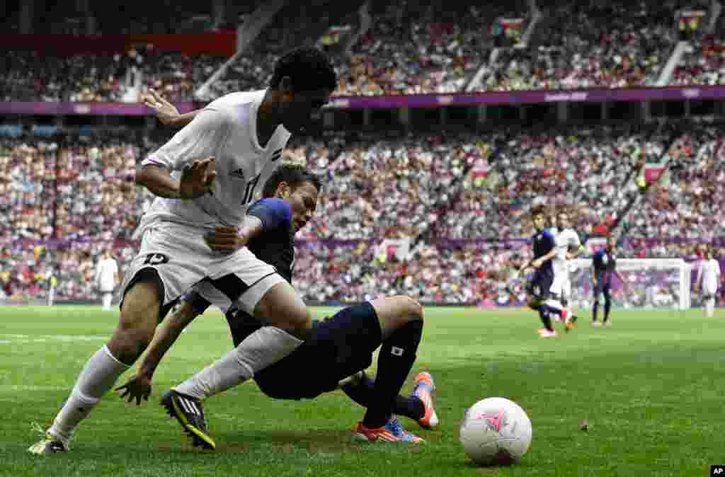 Mohamed El Neny de l'Egypte, à gauche, accroché par Keigo Higashi du Japon, au centre, lors du match de football des quarts de finale entre le Japon et l'Egypte dans les Jeux olympiques de 2012, le samedi 4 août 2012, à Old Trafford à Manchester, en Angleterre. (AP Photo / Ben Curtis)