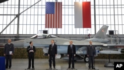 (G) Le général Slawomir Szczepaniak, chef de l'inspection des Armements de l'armée polonaise, l'ambassadeur américain en Pologne Stephen D. Mull et d'autres responsables devant un F-16