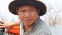 Fut Kheun, 40, a villager affected by the Chinese-built 400-megawatt Lower Sesan 2 Dam, drives a motorized boat to see the submerged villages, in Stung Treng province, March 10, 2020. (Sun Narin/VOA Khmer)