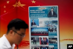 FILE - A man walks by a government billboard promoting Chinese President Xi Jinping's signature "Belt and Road" initiative, outside a subway station in Beijing, China, Aug. 28, 2018.