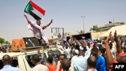 Des manifestants soudanais, brandissant le drapeau national, participent à un sit-in devant le quartier général de l'armée à Khartoum, le 5 mai 2019.