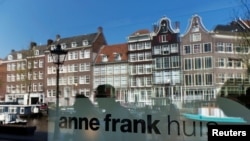 FILE - Reflections of tourists and canal houses are seen in the window of the Anne Frank museum in Amsterdam, April 24, 2013. 