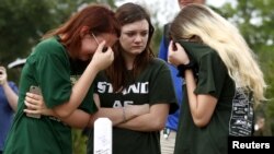 FILE - Mourners gather at a makeshift memorial left in memory of the victims killed in a shooting at Santa Fe High School in Santa Fe, Texas, May 21, 2018. 