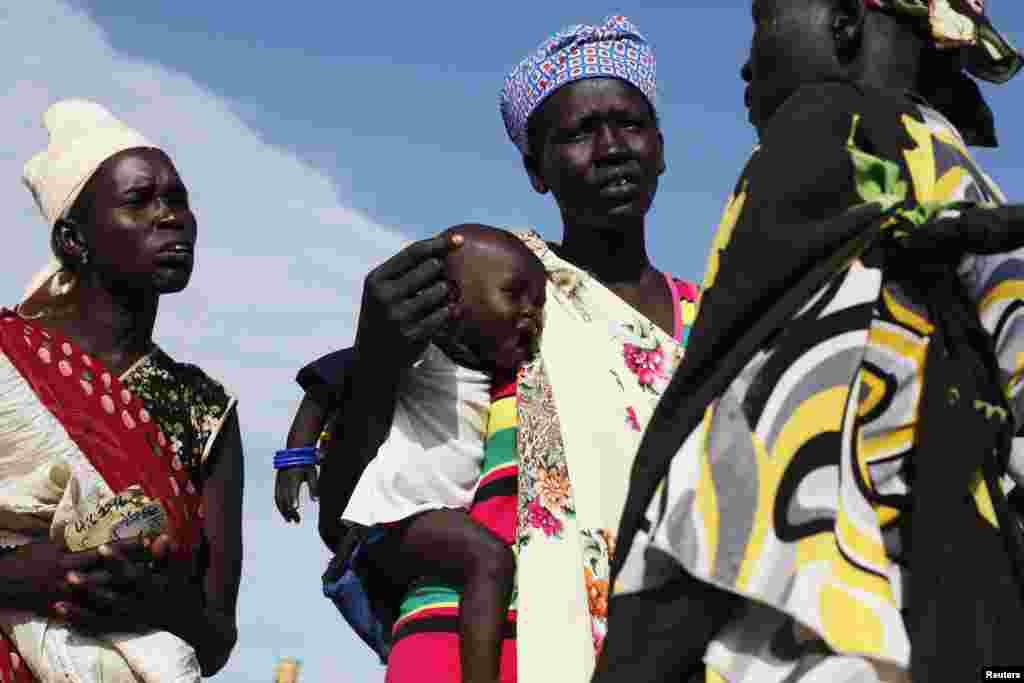 Une femme porte un bébé alors qu’elle discute avec une autre femme au centre de distribution alimentaire à Minkaman, Etat de Lacs, Sud Soudan, le 27 juin 2017. (Reuters)