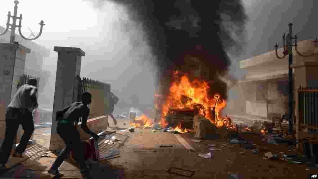 Des manifestants mettent le feu au Parlement à Ouagadougou le 30 octobre 2014. Des centaines de manifestants en colère au Burkina Faso ont pris d'assaut le parlement le 30 octobre avant d'y mettre le feu en protestation contre l'intention de modifier la Constitution pour permettre au Président Blaise Compaoré pour étendre son règne de 27 ans. La police a tiré des gaz. AFP PHOTO / ISSOUF SANOGO