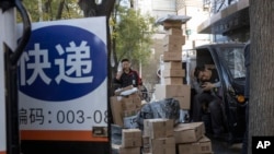 中國“光棍節”當天，北京街頭快遞小哥在分發運送包裹（2019年11月11日美聯社資料照）