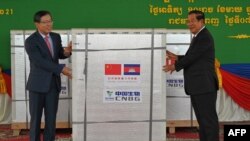 China's ambassador to Cambodia Wang Wentian (L) hands over a shipment of Sinopharm Covid-19 coronavirus vaccine to Cambodian Prime Minister Hun Sen (R) during a ceremony at Phnom Penh International Airport in Phnom Penh on February 7, 2021. (Photo by TANG CHHIN Sothy / AFP) 