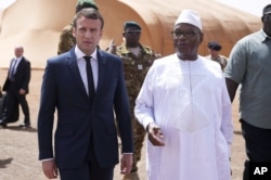 Le président français Emmanuel Macron, à gauche, s'entretient avec le président malien Ibrahim Boubacar Keita alors qu'ils rencontrent des soldats français de l'opération Barkhane, la plus grande opération militaire française, dans le nord du Mali, le 19 mai 2017.