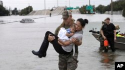 Un membre de l'unité d'élite du SWAT de Houston, Daryl Hudeck, porte secours à Catherine Pham et son fils de 13 mois Aiden en les prenant dans ses bras, après les avoir secourus de leur maison inondée suite au passage de Harvey, le 27 août 2017.