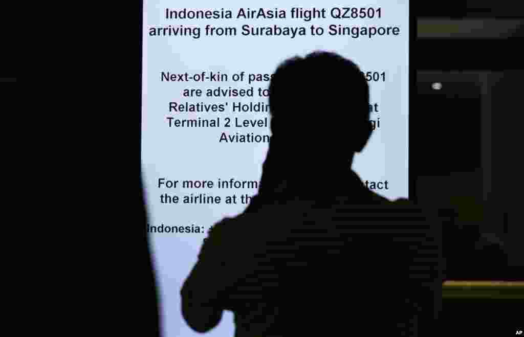 A man is silhouetted against an electronic sign board instructing relatives and next-of-kin to gather at a holding area at the Changi International Airport in Singapore, where AirAsia Flight 8501 from Surabaya, Indonesia was scheduled to land, Dec. 28, 2014 .