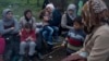 Stranded in the northern Greek border station of Idomeni for 15 days, Syrian refugees sit next to a fire as they wait to be allowed to cross to Macedonia, March 5, 2016.