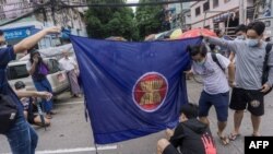 2021年6月14日，在仰光參加反對軍事政變快閃示威的抗議者準備焚燒東盟旗幟（法新社）。
