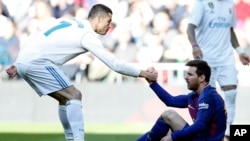 Cristiano Ronaldo aide Leonel Messi à se relever lors d'un match entre le Real Madrid et le FC Barcelone, Espagne, le 23 décembre 2017