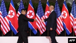 ប្រធានាធិបតី​អាមេរិក​លោក Donald Trump ដើរ​ទៅចាប់ដៃ​ជាមួយ​មេដឹកនាំ​កូរ៉េ​ខាង​ជើង​លោក Kim Jong Un នៅ​ក្នុង​ប្រទេស​សិង្ហបុរី​កាលពី​ថ្ងៃទី​១២ ខែ មិថុនា ឆ្នាំ ២០១៨។