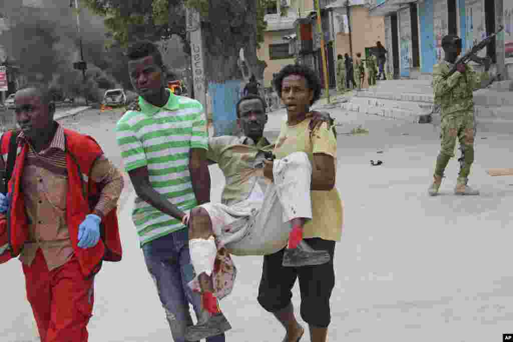 Deux civils somaliens emmènent un blessé de l'attentat à Mogadiscio, en Somalie, le 30 juillet 2017.