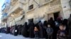 FILE - Women and children queue to receive free meals in Aleppo, Syria, Feb. 2, 2017. 