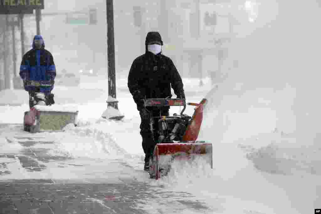 Workers try to clear snow from city sidewalks during a winter snowstorm in Boston, Jan. 27, 2015.